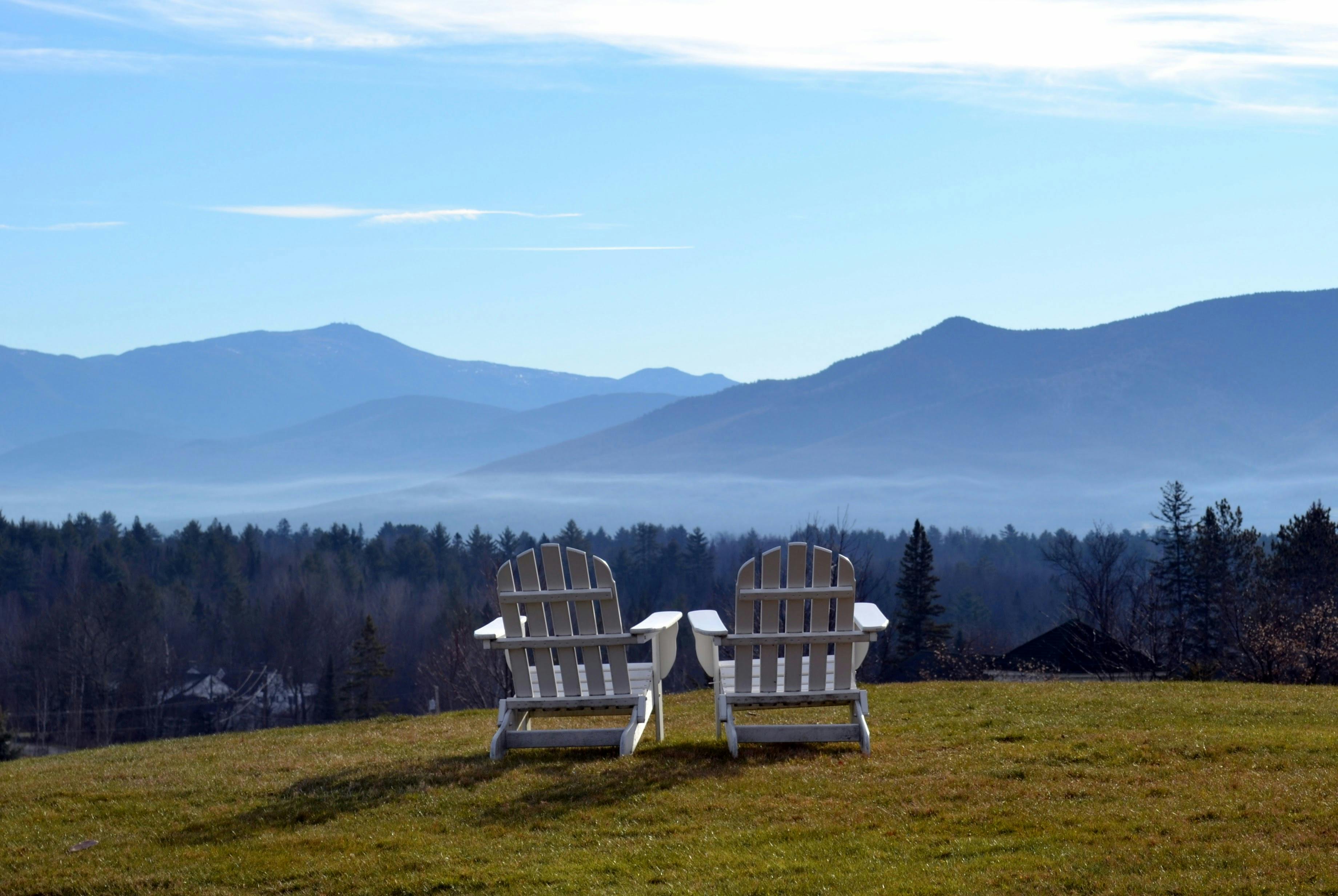 Two Adirondack chairs overlooking a misty mountain range